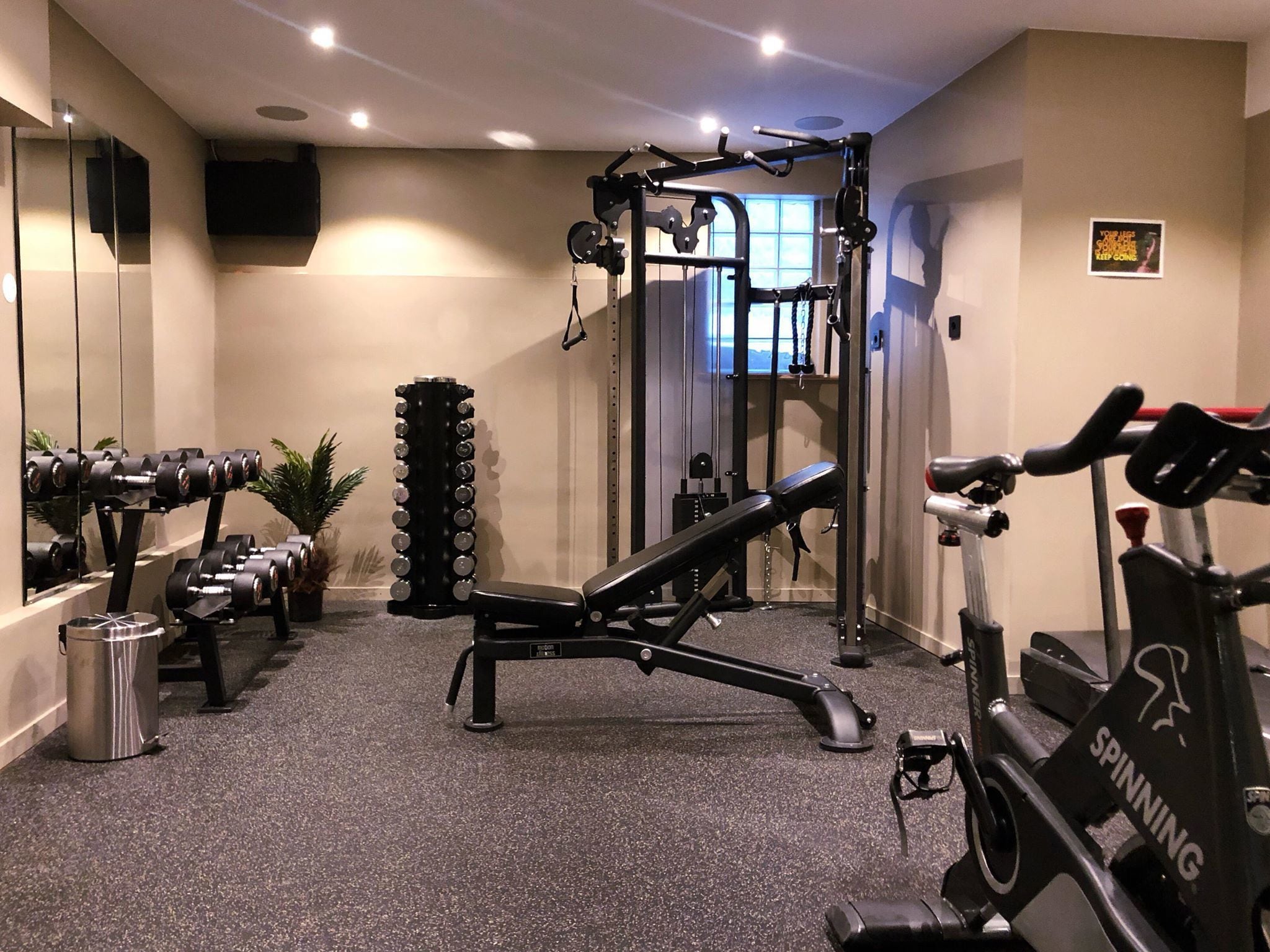 Un gimnasio con equipamiento de ejercicio, una banca, una bicicleta estática y un espejo.