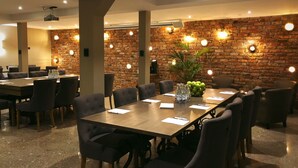 A conference room with a brick wall, round table, and chairs. - Hotell Nordic (Norrköping)