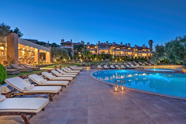 A resort with a swimming pool, lounge chairs, and a well-lit building. - Kassandra Village Resort (Kassandra)