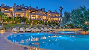 Una piscina al aire libre, sombrillas, sillones reclinables de piscina