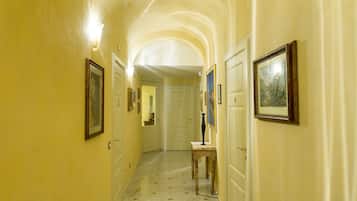 Un corridoio con pavimento in marmo, quadri appesi alle pareti e un tavolo in legno.