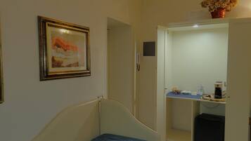 Een slaapkamer met een bed, een lijst met een schilderij, een kledingkast met spiegel en een vaas met bloemen.