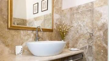 A bathroom with a large mirror, a white sink, and marble walls.
