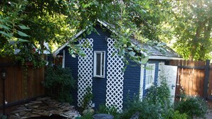 A wooden deck with a small garden area, a stone wall, and a white lattice structure. - River Wynde Executive B&B (Calgary)