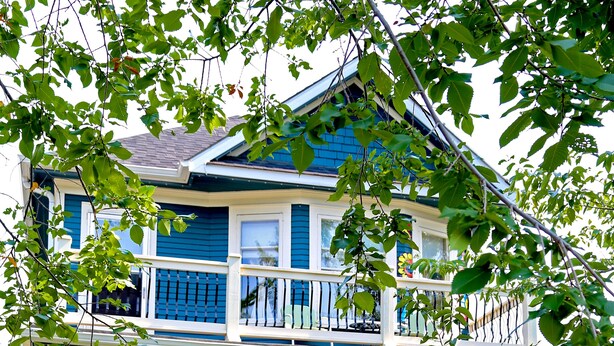 A two-story house with a front porch, a balcony, and a well-maintained garden. - River Wynde Executive B&B (Calgary)