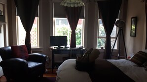 A bedroom with a bed, a desk with a computer, a chair, and a standing lamp. - River Wynde Executive B&B (Calgary)