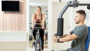 Un gimnasio con bicicletas estáticas y una máquina de ejercicios sentada.