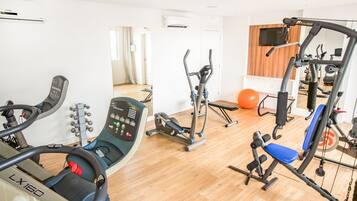 Un gimnasio en casa con varios equipos de ejercicio, incluyendo una cinta de correr, una elíptica y máquinas de pesas.
