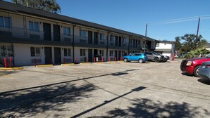 A motel with a row of rooms, a parking lot, and a few cars parked. - Southmore Boulevard Motel (Houston)