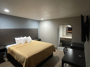 A hotel room with a bed, bedside table, desk, and a mirror. - Southmore Boulevard Motel (Houston)