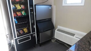 A vending machine with snacks and a small refrigerator. - Southmore Boulevard Motel (Houston)
