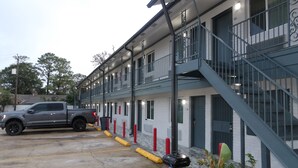 A motel with a parking lot, a grey pickup truck, and potted plants. - Southmore Boulevard Motel (Houston)