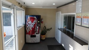 A hallway with a vending machine, a potted plant, and a reception desk. - Southmore Boulevard Motel (Houston)