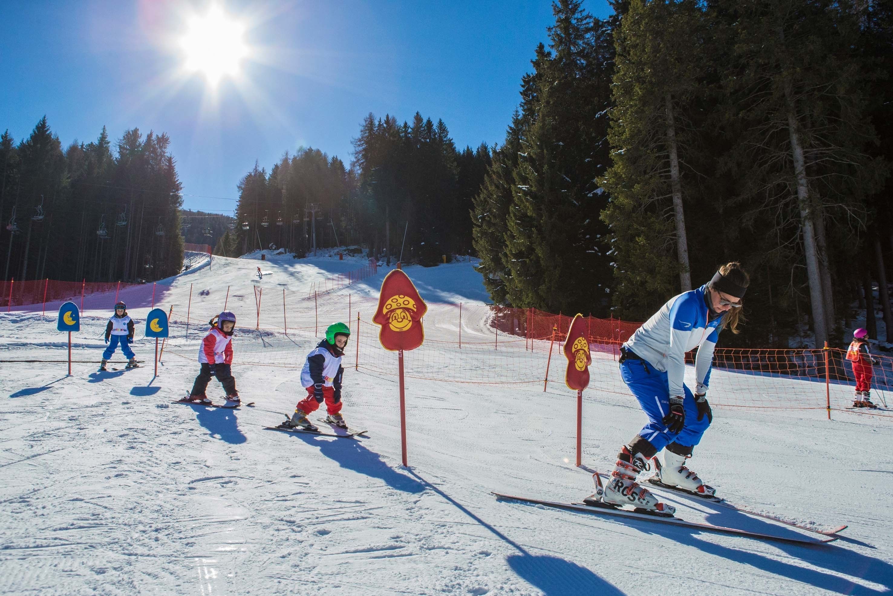 A ski slope with skiers and a ski lift in the background.