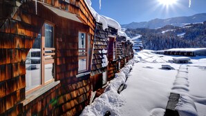 Eine Holzhütte mit schneebedecktem Dach und freiem Blick auf die verschneite Landschaft.