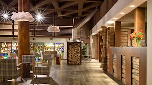 Eine Lobby mit einem Holzbüro, Karo-Stühlen, Holzboden und einem Buntglasfenster im Hintergrund.