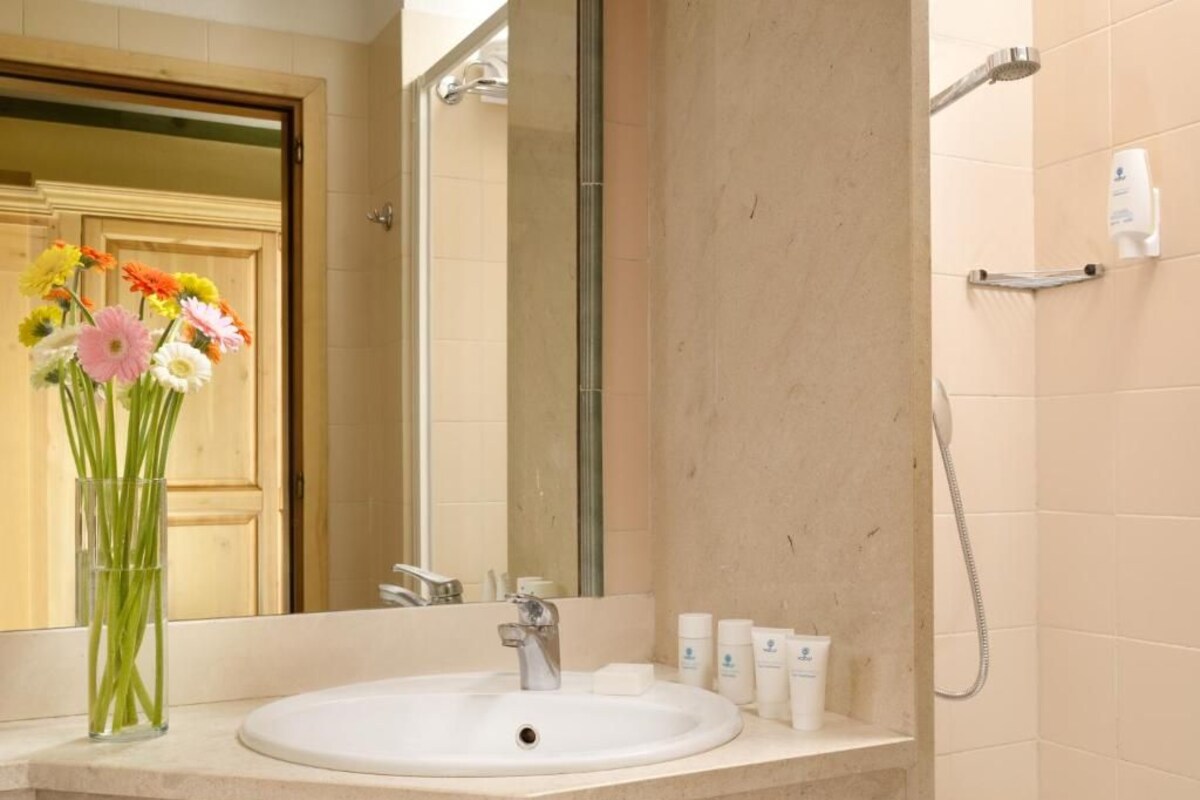 A bathroom with a sink, mirror, and shower.