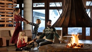 Gemütliche Innenansicht mit einem Feuerkorb, Holzmöbeln und großen Fenstern mit Blick auf Schnee.