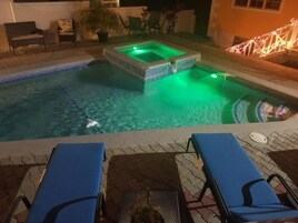 Uma piscina com hidromassagem, espreguiçadeiras e um pequeno deck.