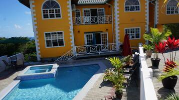 A two-story yellow building with a swimming pool and outdoor seating area.
