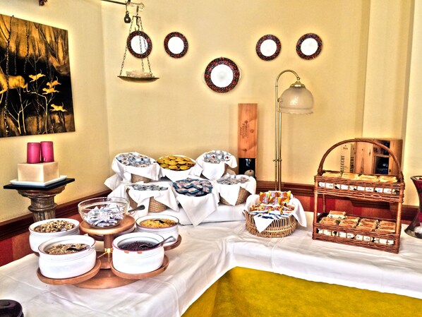 A buffet table with various food items and a painting on the wall.