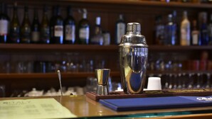 A bar area with a cocktail shaker, a small glass, and a menu on the counter. - IHR Hotel Villa Emma (Canazei)