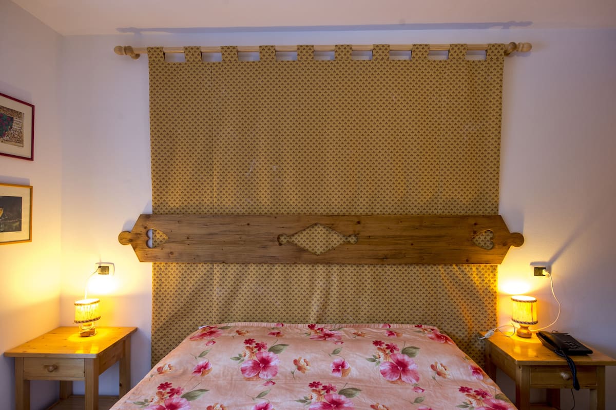 A room with a bed, two bedside tables, and a wall-mounted headboard.