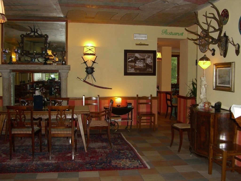 A cozy restaurant interior with wooden furniture, a patterned rug, and wall-mounted lamps.