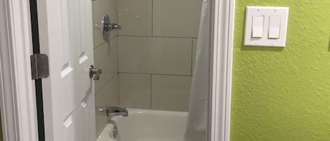 Un baño con ducha, bañera y retrete.