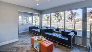 A modern waiting area with a herringbone wood floor, leather seating, and large windows offering a view of the street.
