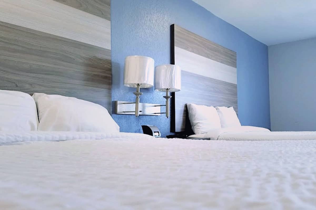 A hotel room with a large bed, two bedside lamps, and a modern wall design.