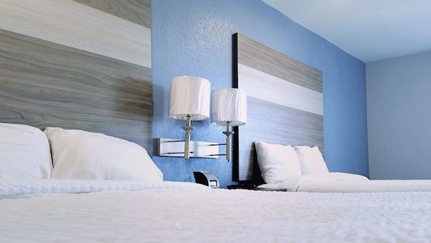 A hotel room with a large bed, two bedside lamps, and a modern wall design.