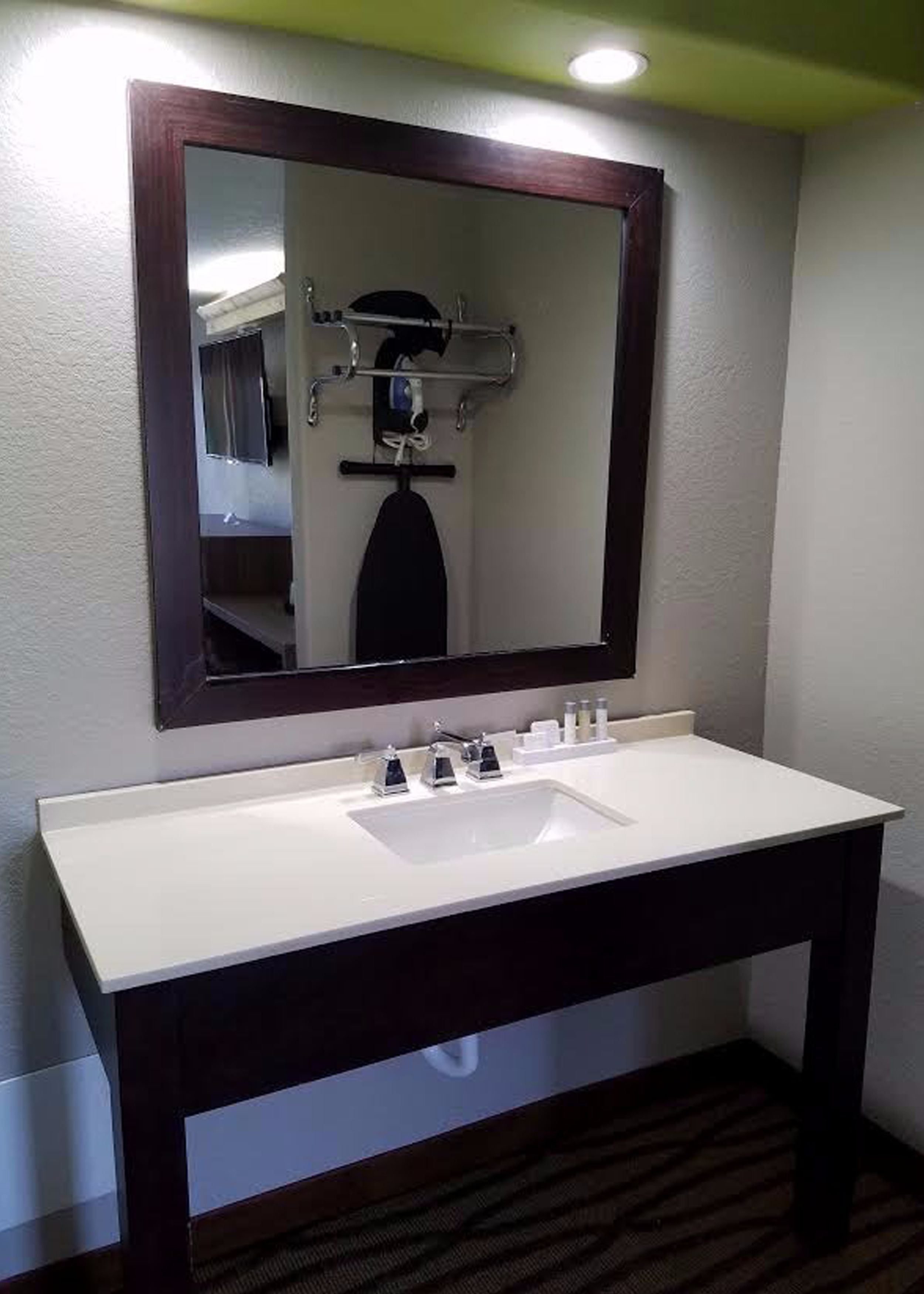 A bathroom with a white sink, dark vanity, and a mirror with a wooden frame.