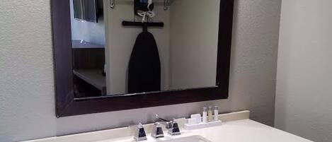 A bathroom with a white sink, dark vanity, and a mirror with a wooden frame.