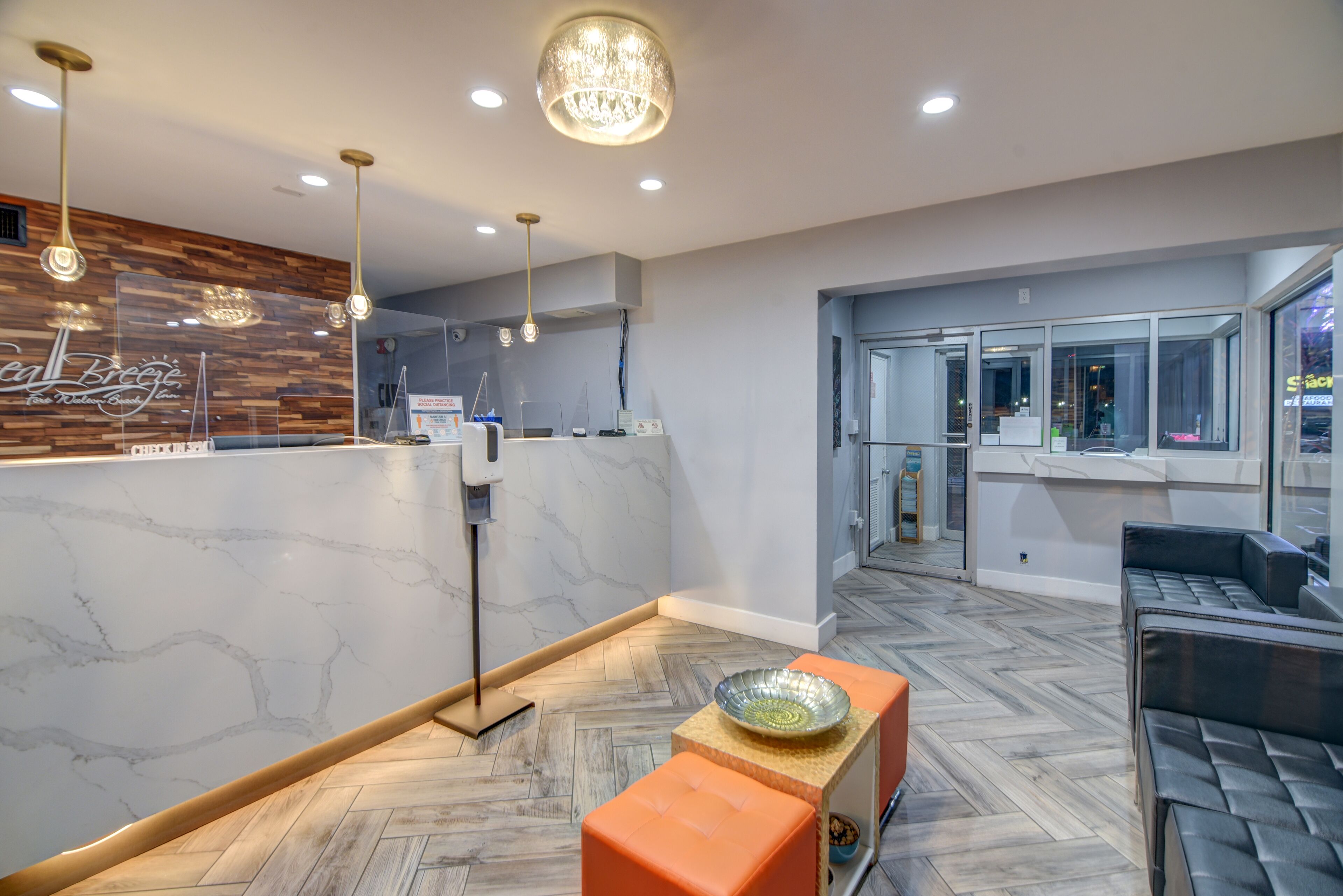 Uma área de recepção moderna com balcão de mármore, detalhes de parede em madeira e um padrão de piso em padrão herringbone.
