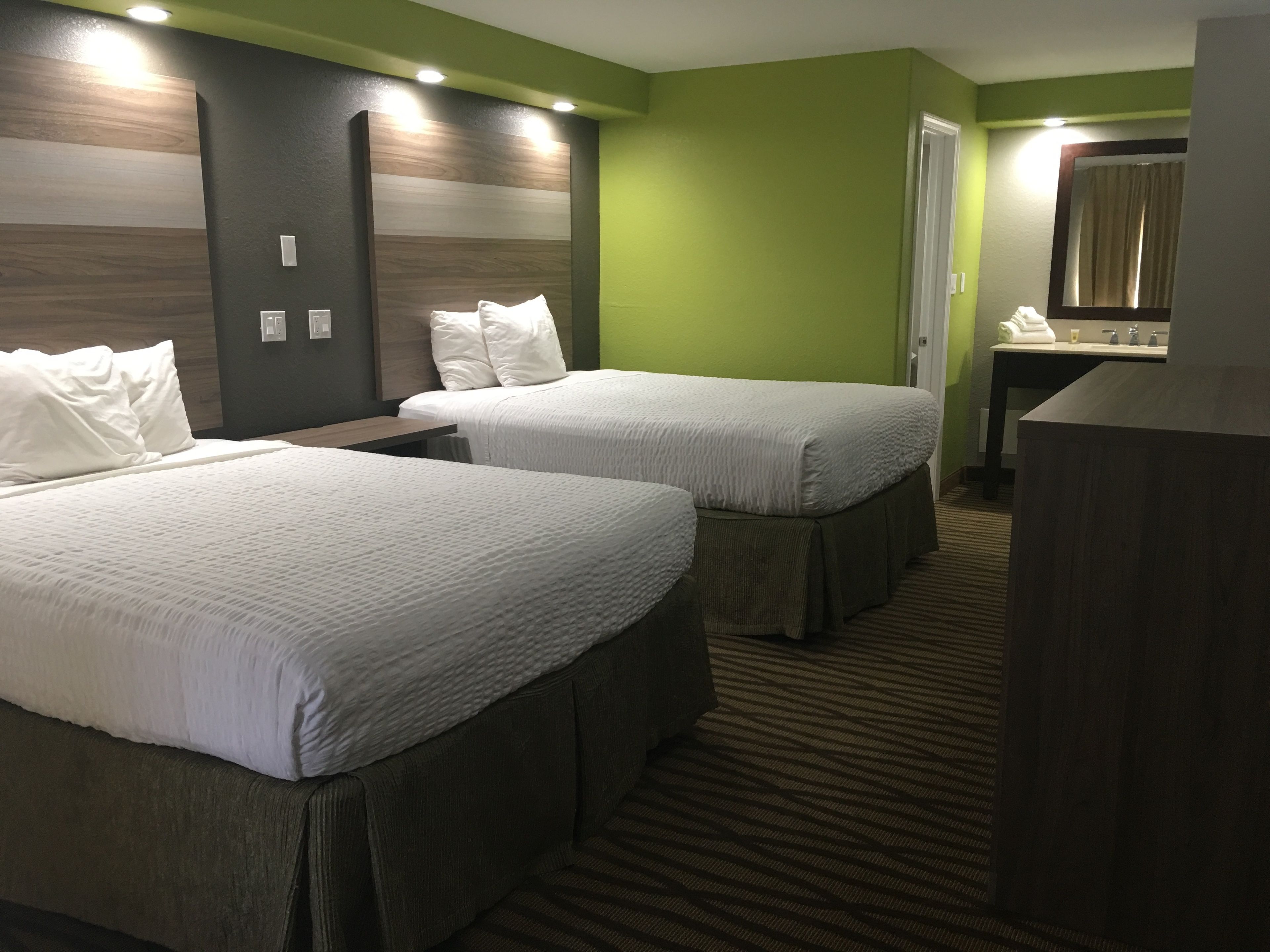 Ein Hotelzimmer mit zwei Betten, einem Schreibtisch und einem Spiegel.