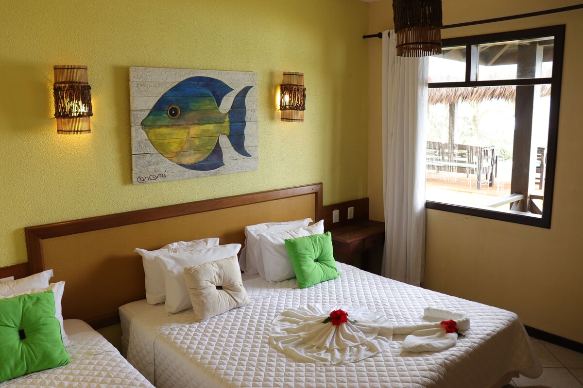 A hotel room with two beds, a painting of a fish on the wall, and a view of the outside.
