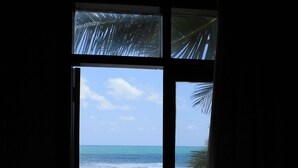 A window with a view of the ocean, beach, and a gazebo. - Anaui Pousada (Ipojuca)