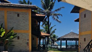 A swimming pool with a tiled deck, palm trees, and a building with a tiled roof. - Anaui Pousada (Ipojuca)