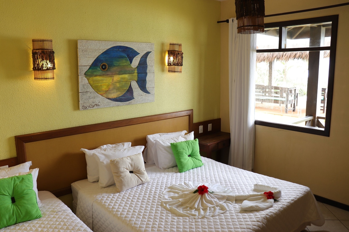 Habitación de hotel con dos camas, un cuadro de un pez en la pared y vistas al exterior.