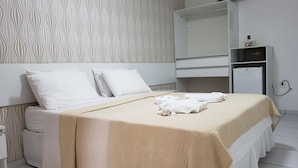 A hotel room with a bed, white bedding, a large mirror, a wardrobe, and a towel rack. - Pousada Ouriço (Ipojuca)