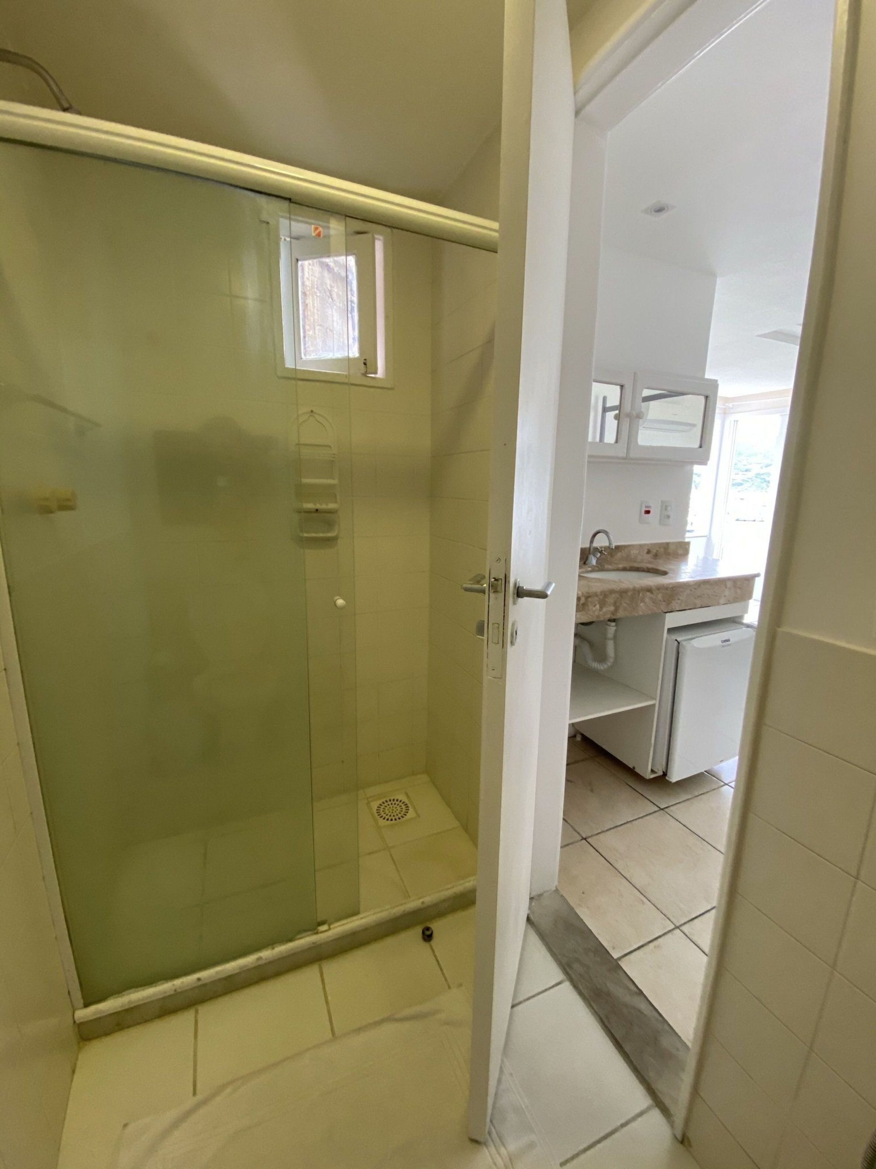 A bathroom with a glass shower enclosure, a toilet, and a sink with a countertop.