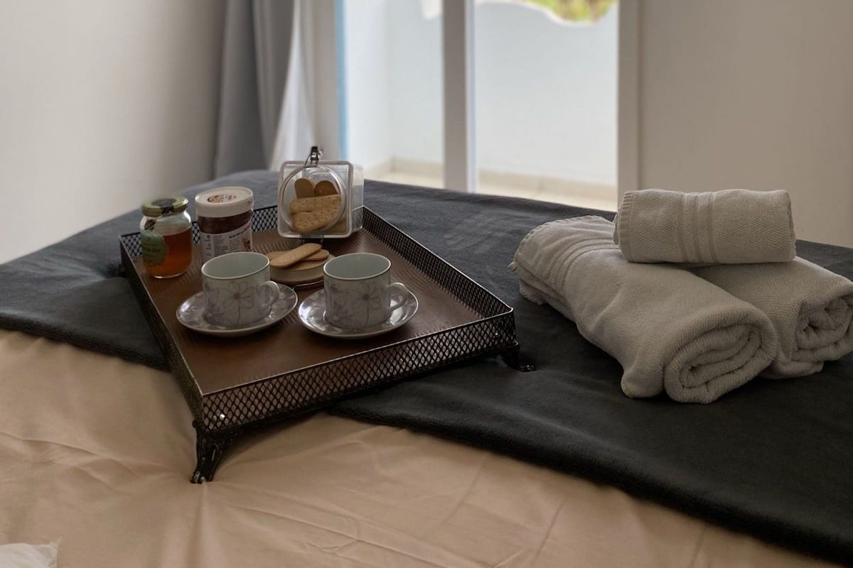 Habitació d'hotel amb un llit, una bandeja amb te i galetes, i vista a zones verdes a l'exterior.