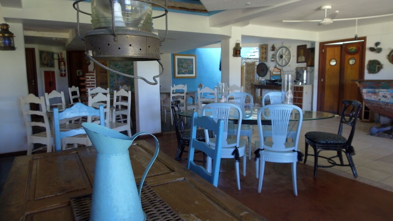 A dining area with a round table and chairs, a hanging light fixture, and a blue wall with a painting.