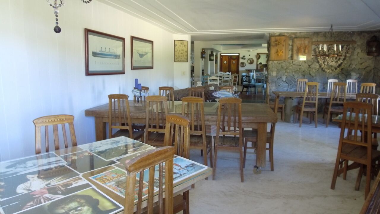 A dining area with wooden tables and chairs, framed artwork on the walls, and a stone accent wall.