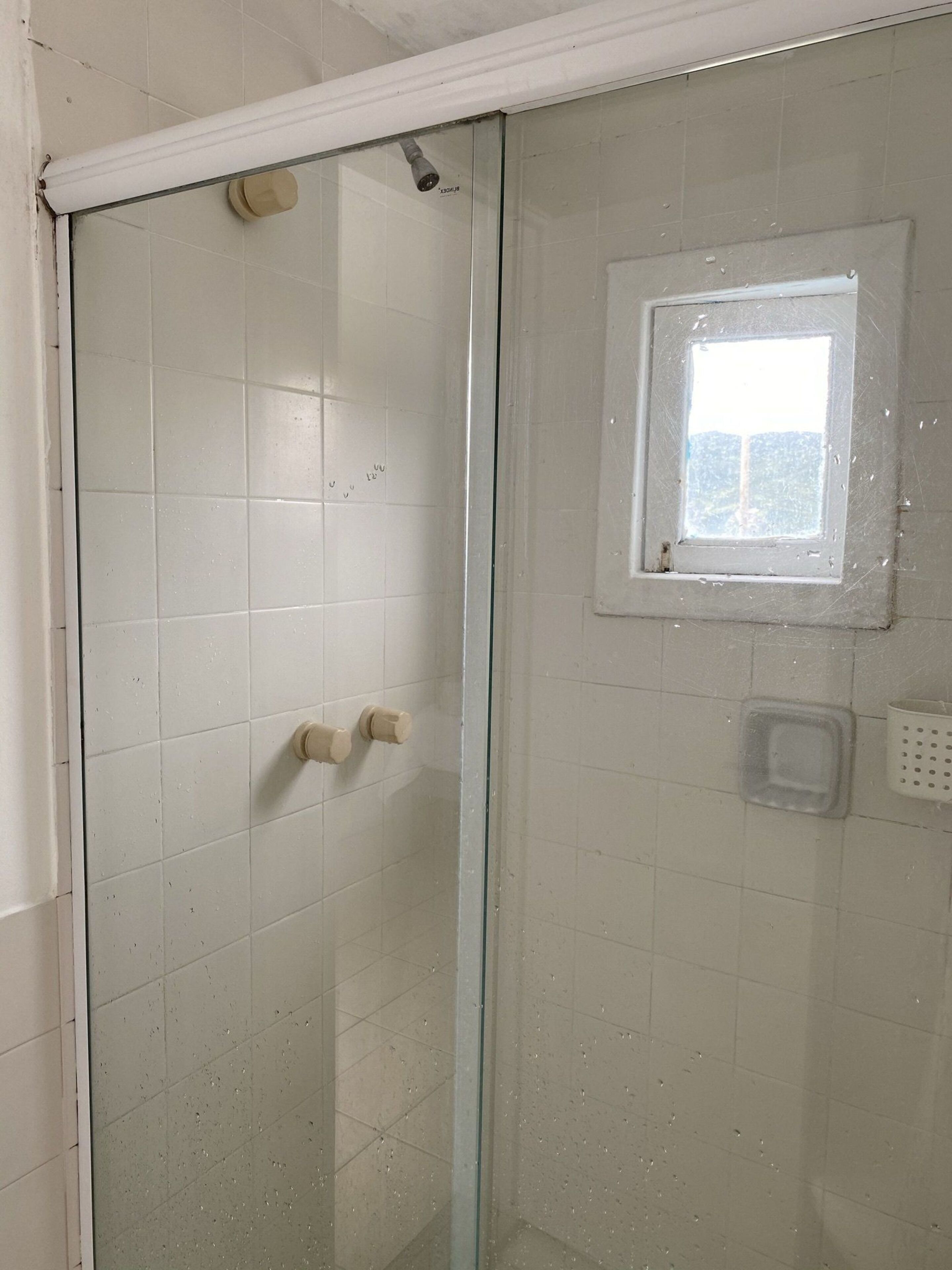 A shower with a glass door, a small window, and a showerhead.
