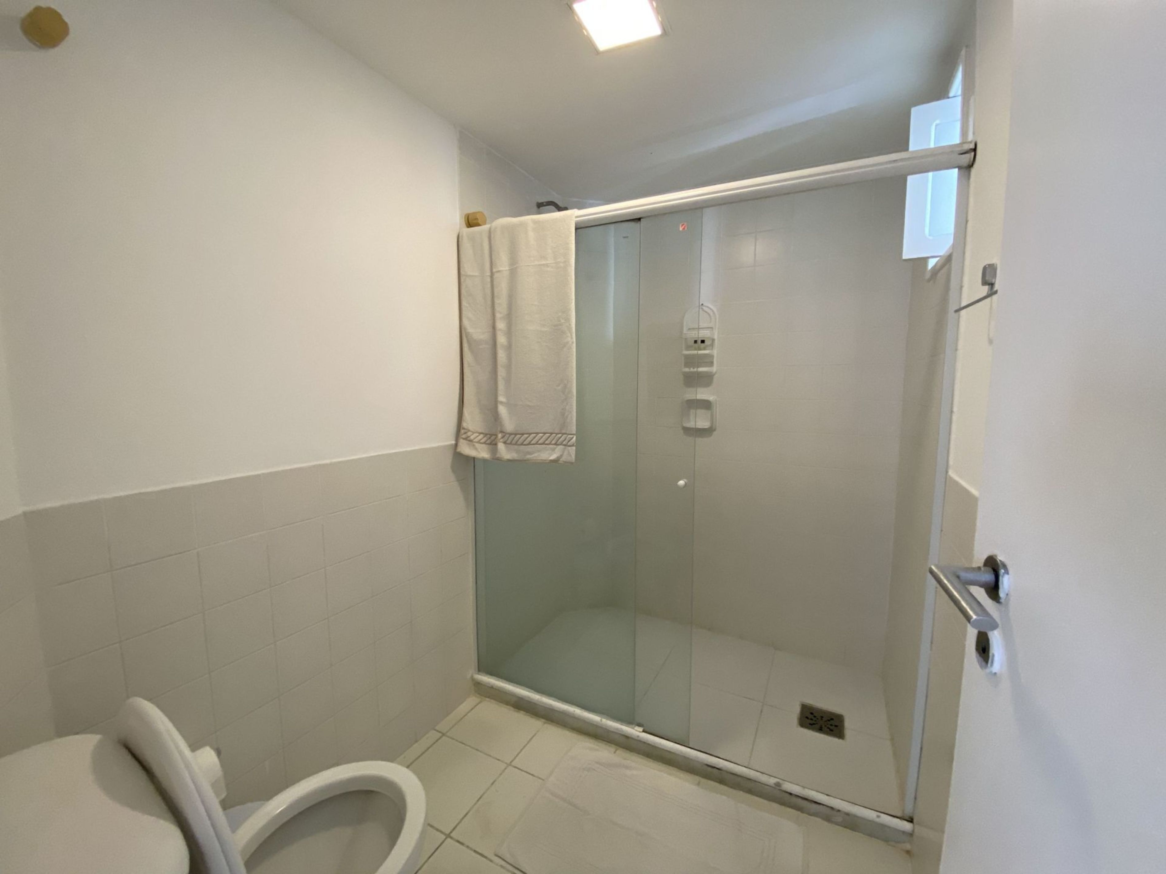 A bathroom with a shower, toilet, and a towel hanging on the wall.