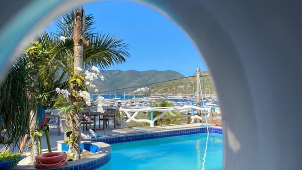 Une piscine avec vue sur un port de plaisance et, au loin, sur des montagnes.