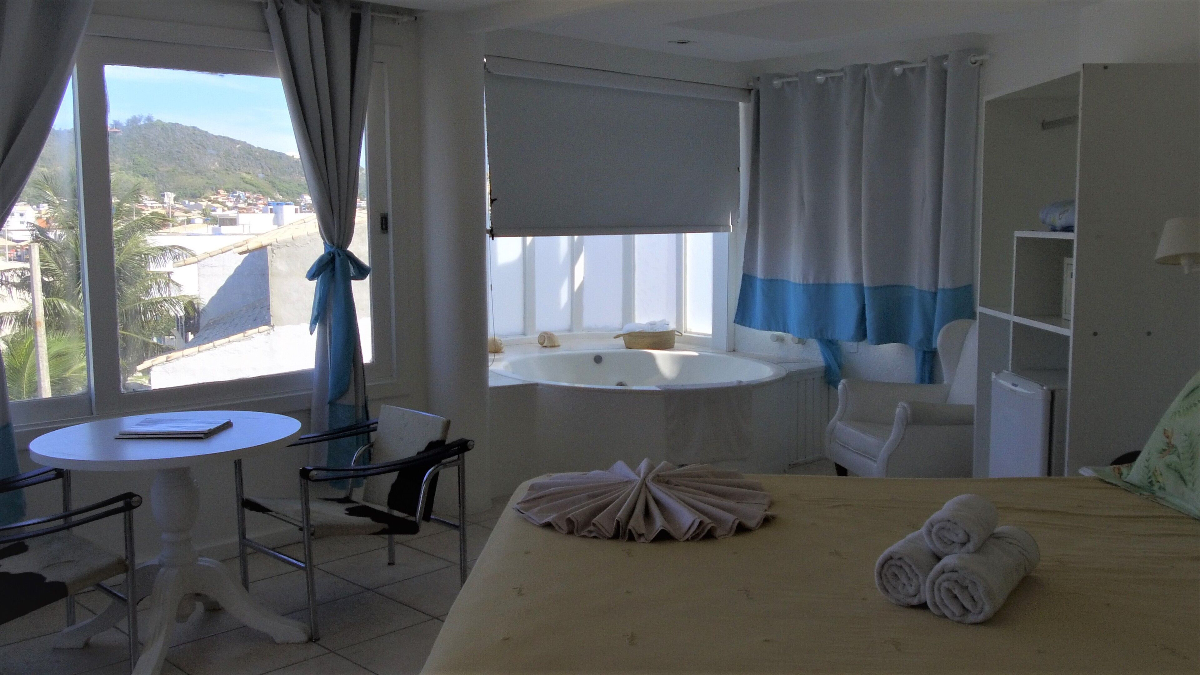 Et hotelværelse med en seng, et rundt bord, en stol, et badekar og udsigt til et bjerrelandskab.