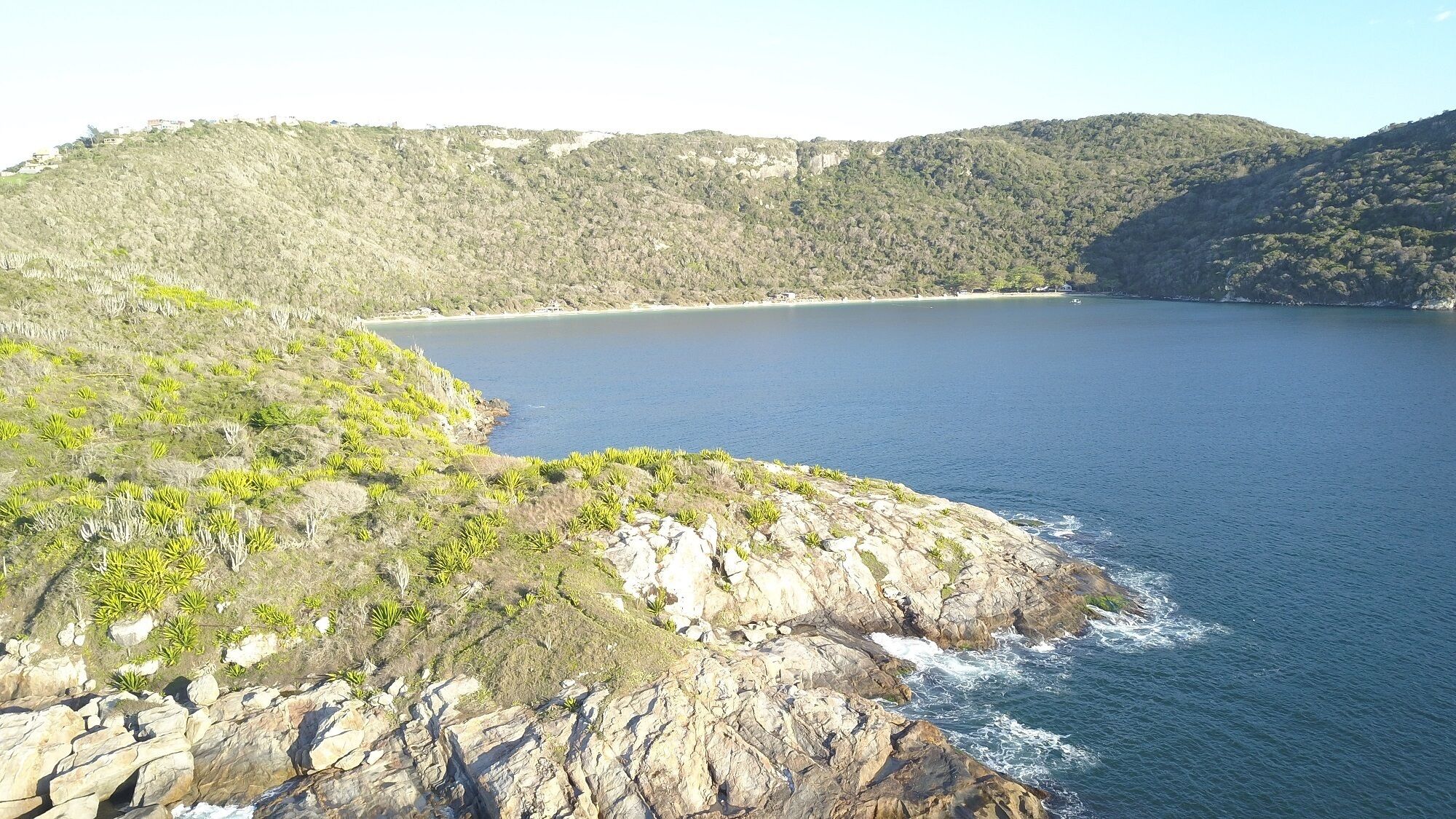 A coastal landscape with rocky terrain and a clear view of the sea.